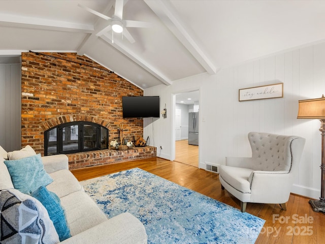 living room with lofted ceiling with beams, ceiling fan, a fireplace, and hardwood / wood-style floors