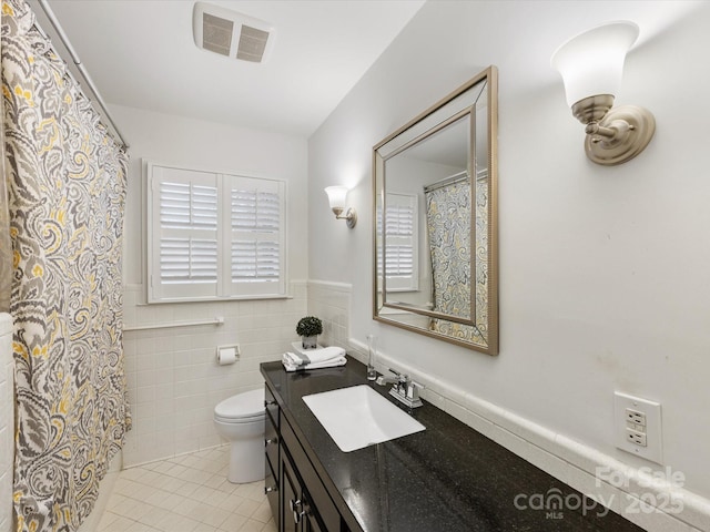 bathroom with tile patterned flooring, vanity, tile walls, and toilet