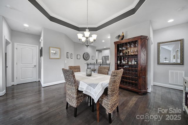 dining room featuring ornamental molding, an inviting chandelier, dark hardwood / wood-style flooring, and a tray ceiling