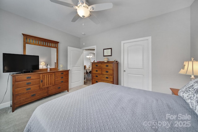 carpeted bedroom with ceiling fan with notable chandelier