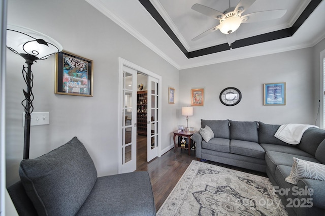 living room featuring ceiling fan, a raised ceiling, crown molding, dark wood-type flooring, and french doors