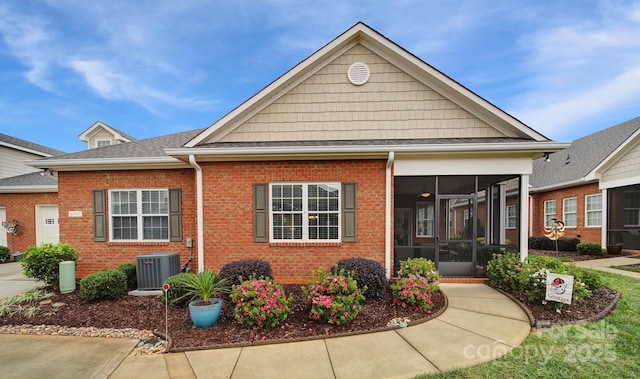 view of front of house with central AC and a sunroom