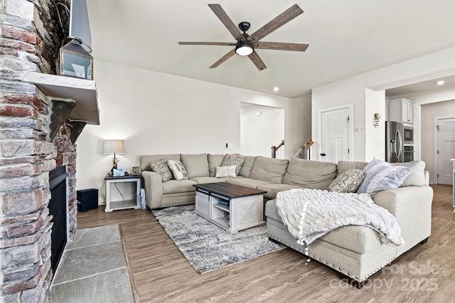 living room featuring a fireplace, wood-type flooring, and ceiling fan