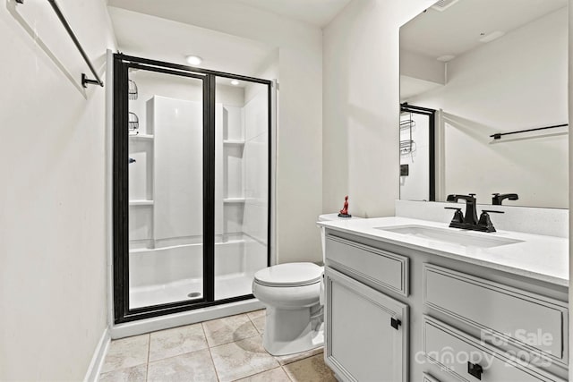 bathroom with a shower with door, vanity, tile patterned floors, and toilet