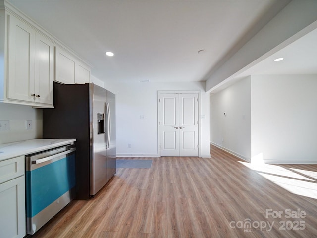 kitchen with appliances with stainless steel finishes, light hardwood / wood-style flooring, and white cabinets