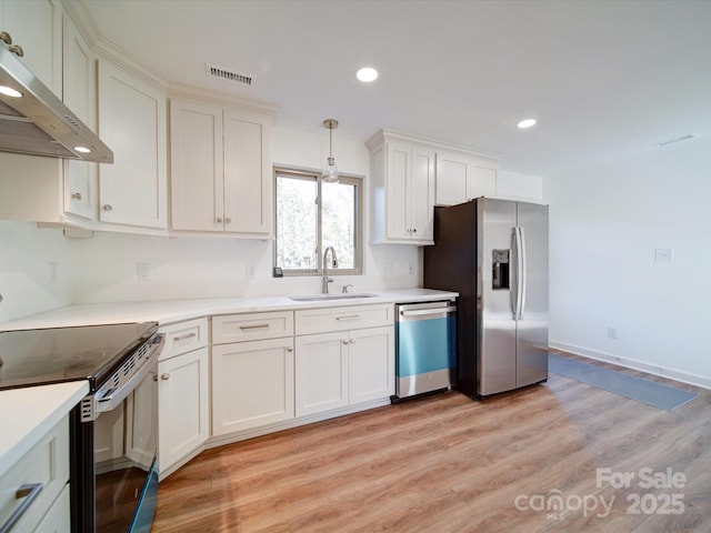 kitchen featuring sink, white cabinetry, decorative light fixtures, light wood-type flooring, and stainless steel appliances