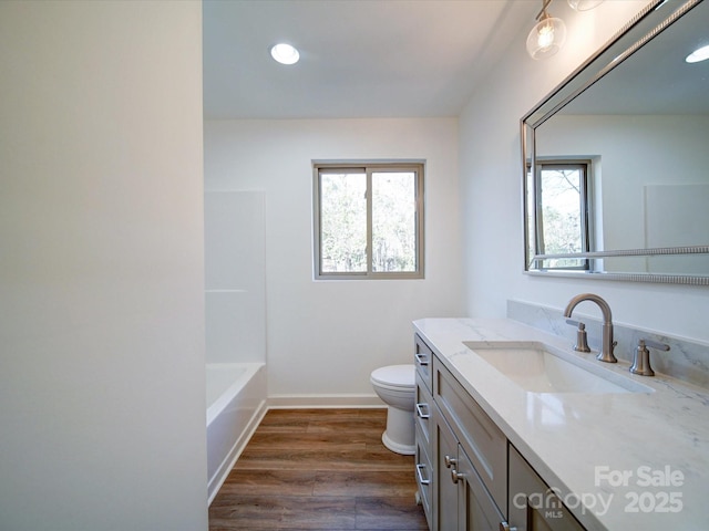 full bathroom with hardwood / wood-style flooring, vanity, toilet, and a wealth of natural light