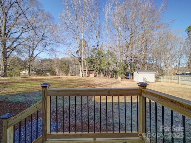 wooden deck featuring a storage shed and a lawn