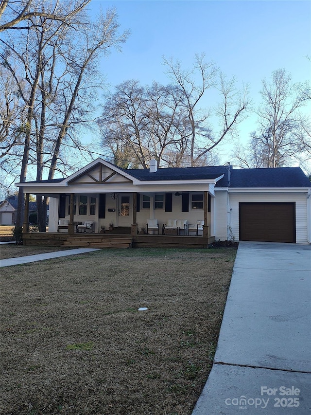 view of front of house with a garage, a front yard, and a porch