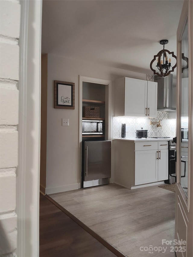 kitchen featuring tasteful backsplash, white cabinetry, an inviting chandelier, and light hardwood / wood-style floors