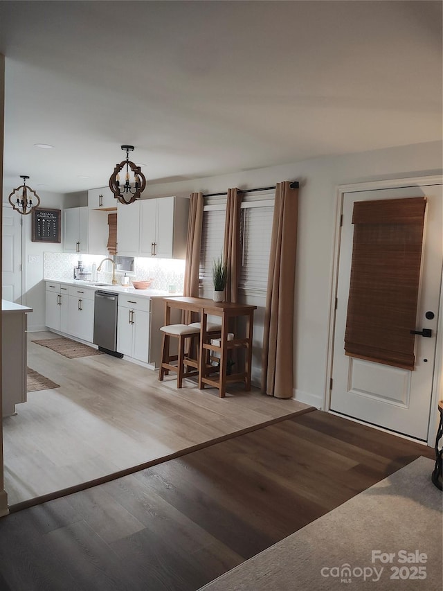 kitchen featuring pendant lighting, dishwasher, light hardwood / wood-style flooring, and white cabinets