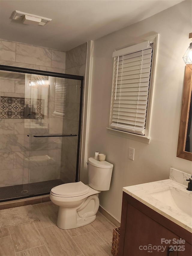 bathroom with an enclosed shower, vanity, and toilet