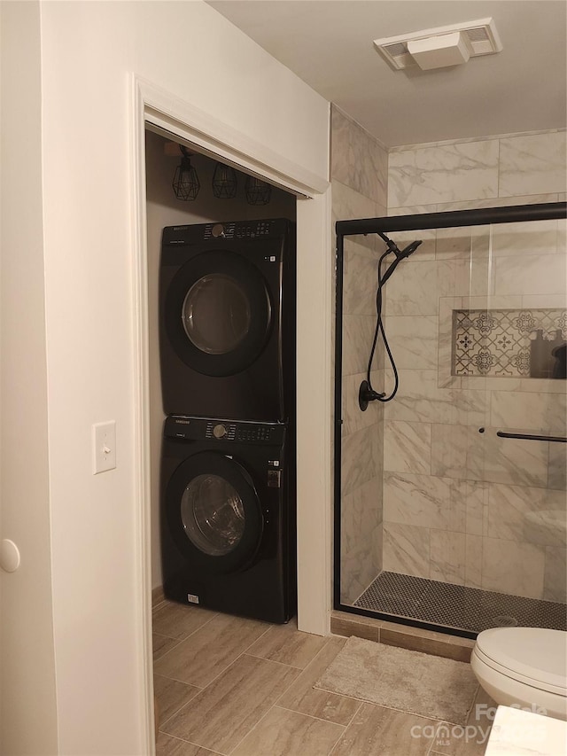 bathroom with stacked washer / dryer, toilet, and walk in shower