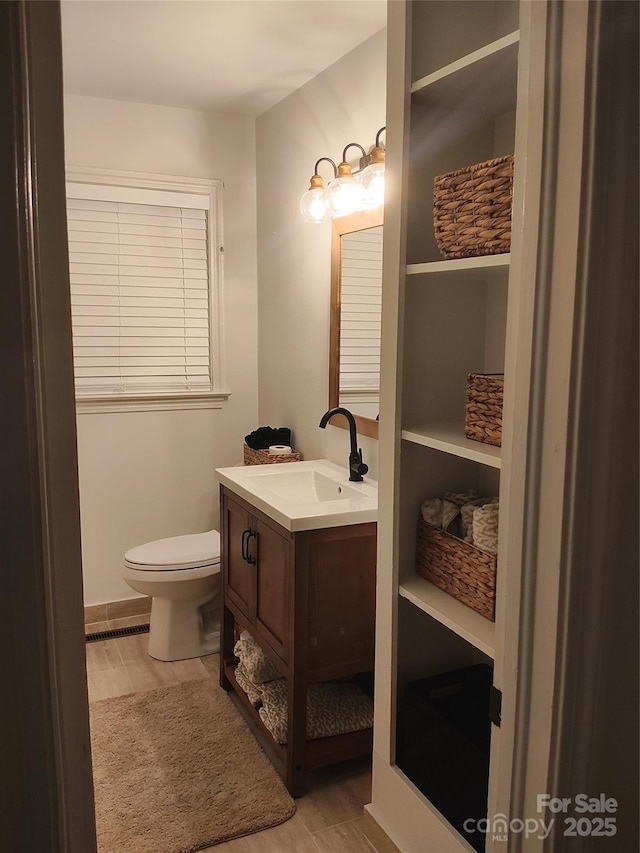 bathroom with hardwood / wood-style flooring, vanity, and toilet