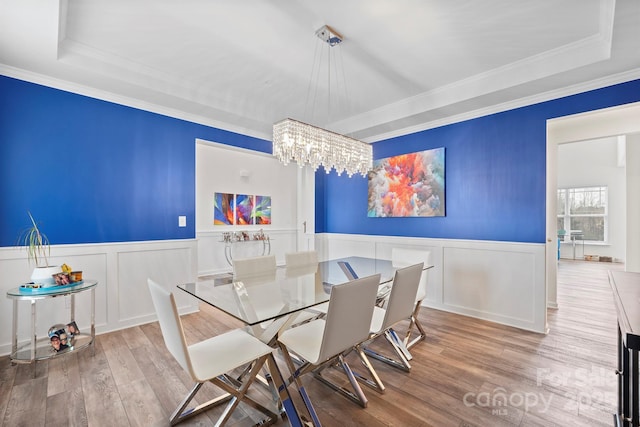 dining room featuring ornamental molding, light hardwood / wood-style floors, an inviting chandelier, and a tray ceiling