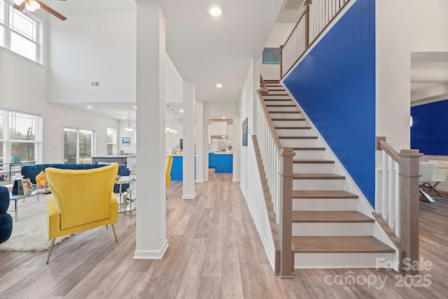 stairs featuring hardwood / wood-style floors and a high ceiling