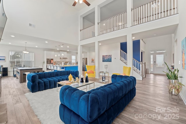 living room featuring ceiling fan, light hardwood / wood-style flooring, and a high ceiling