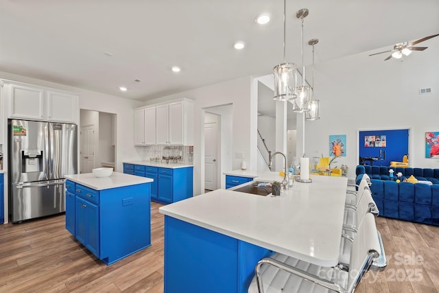 kitchen featuring a kitchen island, blue cabinets, sink, hanging light fixtures, and stainless steel fridge with ice dispenser