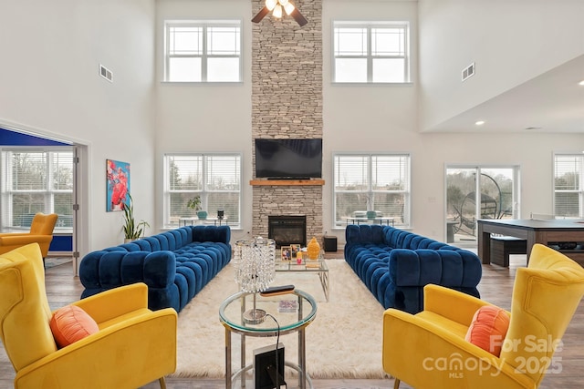 living room with wood-type flooring, a stone fireplace, and plenty of natural light