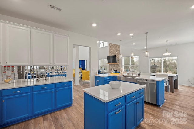 kitchen with white cabinetry, a kitchen island, blue cabinetry, and stainless steel dishwasher