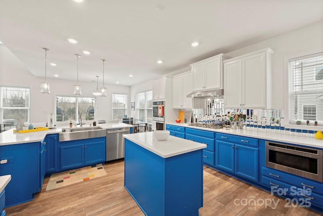 kitchen with pendant lighting, white cabinetry, a kitchen island, stainless steel appliances, and blue cabinets