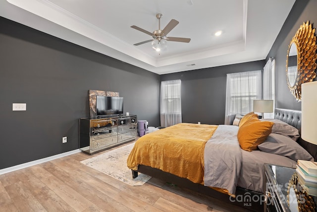 bedroom featuring a raised ceiling, crown molding, ceiling fan, and light hardwood / wood-style floors