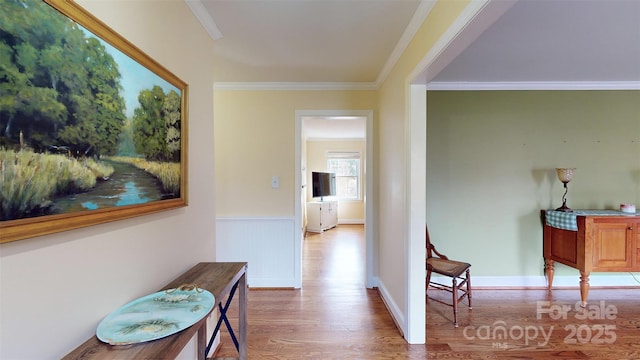 hall with ornamental molding and light hardwood / wood-style floors