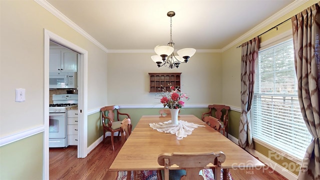 dining room featuring wood-type flooring, ornamental molding, and a notable chandelier