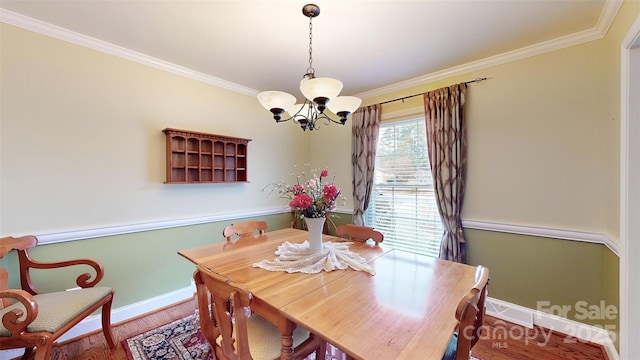 dining space with crown molding, wood-type flooring, and a chandelier