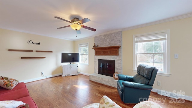 living room with ornamental molding, hardwood / wood-style floors, ceiling fan, and a fireplace