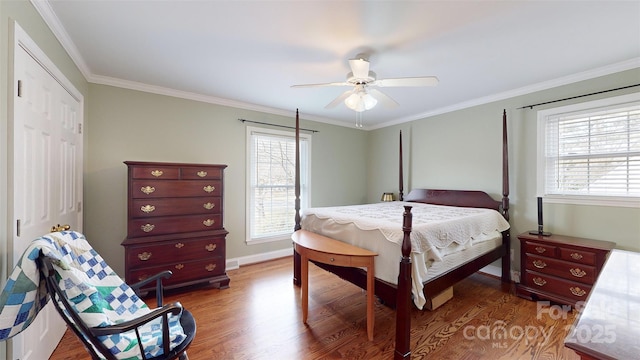 bedroom featuring crown molding, ceiling fan, wood-type flooring, and a closet