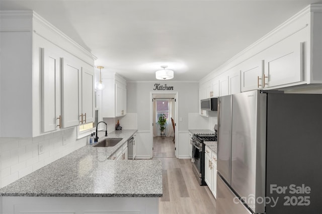 kitchen with stainless steel appliances, light stone countertops, sink, and white cabinets