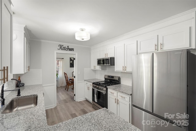 kitchen with white cabinetry, sink, light stone counters, and stainless steel appliances