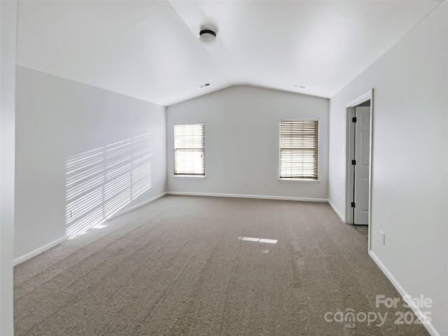 unfurnished room featuring lofted ceiling and light carpet