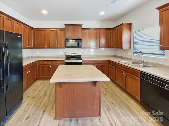 kitchen featuring tasteful backsplash, sink, a center island, light hardwood / wood-style floors, and black appliances