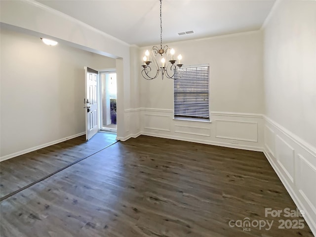 unfurnished dining area with ornamental molding, dark hardwood / wood-style floors, and a notable chandelier