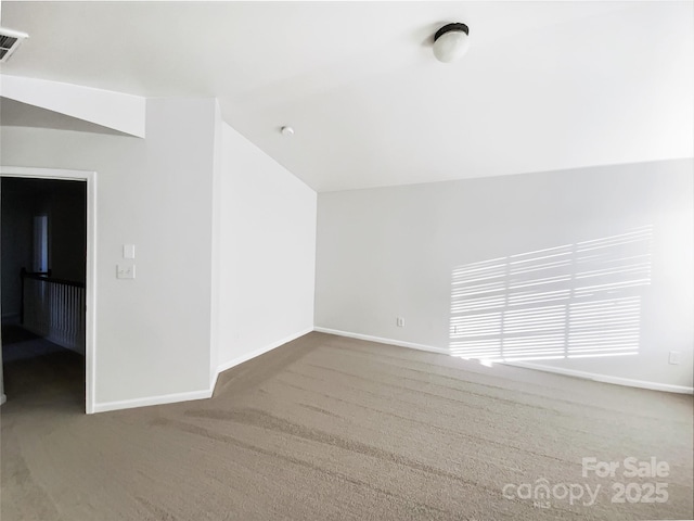 carpeted spare room featuring vaulted ceiling