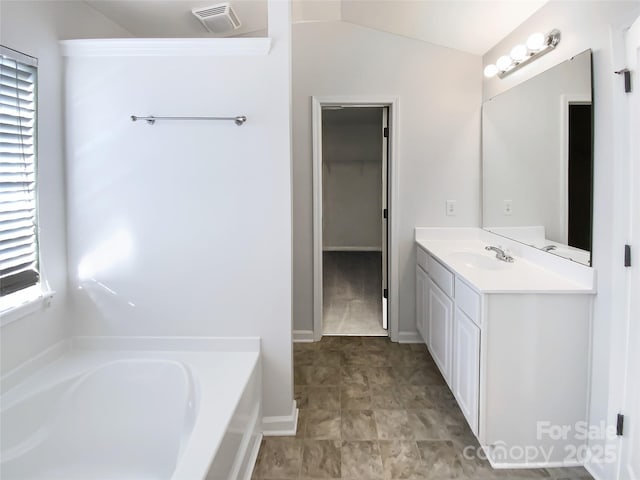 bathroom featuring a bathing tub, vaulted ceiling, and vanity