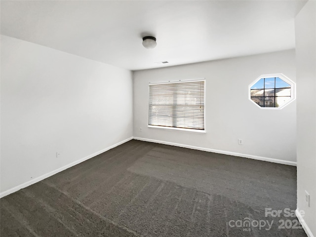 unfurnished room with dark colored carpet