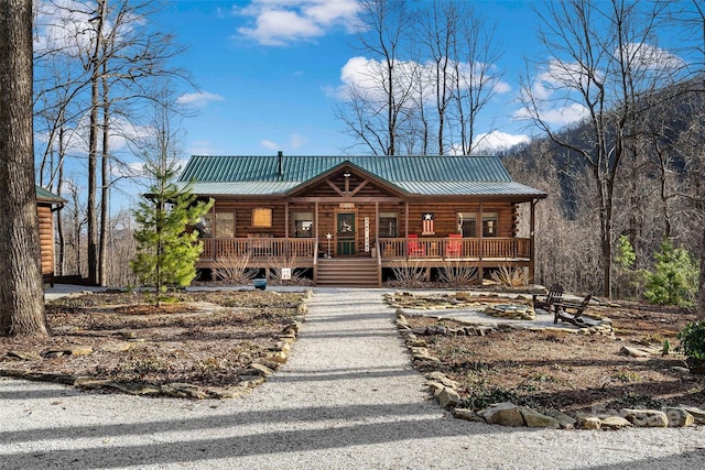 log cabin featuring metal roof, log exterior, and a porch