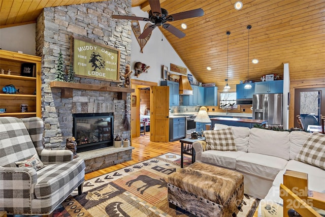 living room featuring ceiling fan, high vaulted ceiling, a fireplace, wooden ceiling, and light wood-type flooring