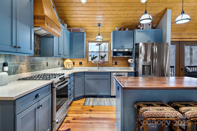 kitchen with blue cabinets, hanging light fixtures, sink, and appliances with stainless steel finishes