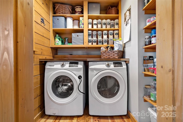 laundry room featuring wood finished floors, laundry area, and separate washer and dryer