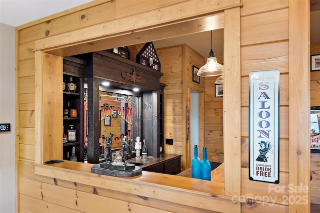 bar featuring wooden counters, wood walls, light brown cabinetry, and decorative light fixtures