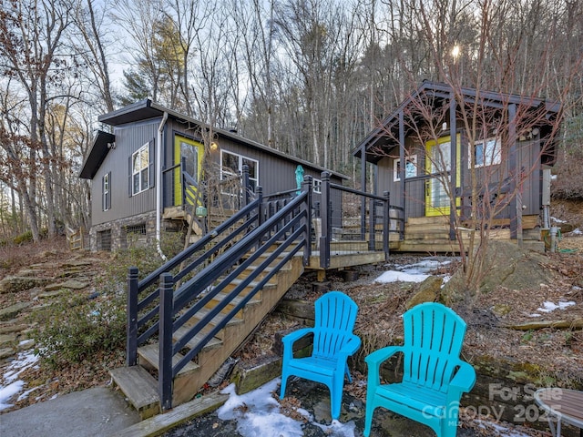 snow covered rear of property featuring a deck