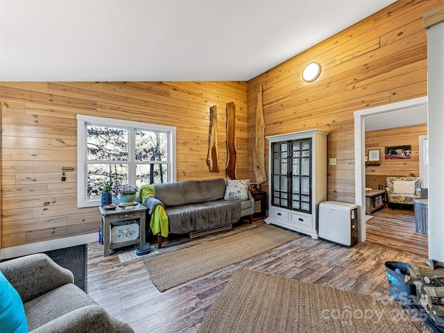 living room with hardwood / wood-style flooring, lofted ceiling, and wooden walls