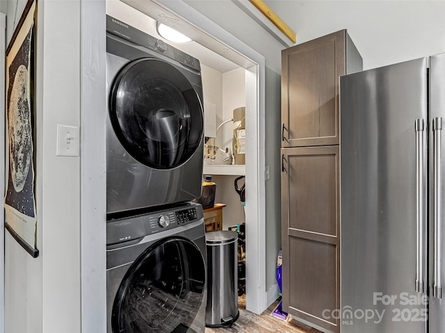 washroom with stacked washer and dryer and light hardwood / wood-style floors