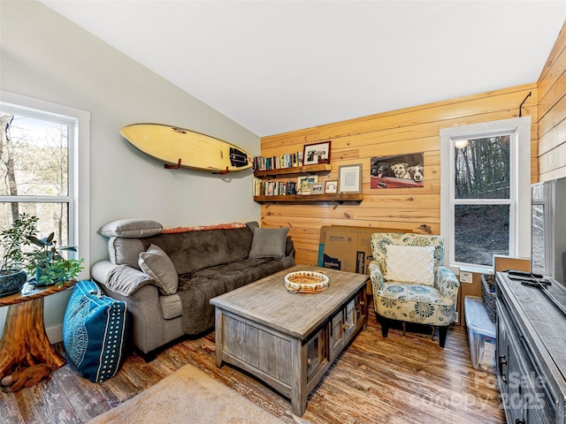 living room featuring hardwood / wood-style flooring, vaulted ceiling, and wood walls