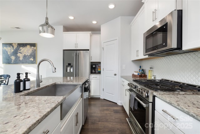 kitchen featuring pendant lighting, appliances with stainless steel finishes, light stone countertops, and white cabinets