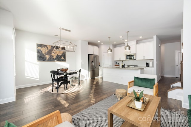 living room featuring dark hardwood / wood-style floors, sink, and an inviting chandelier